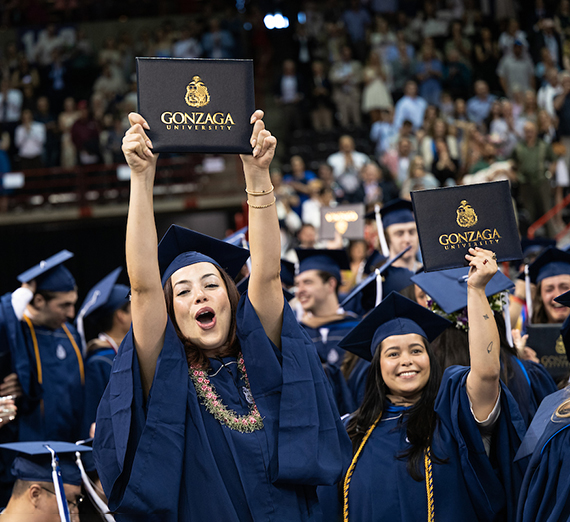 Мужчина опирается на кирпичную стену, за ним — дерево с вишневыми цветами.
